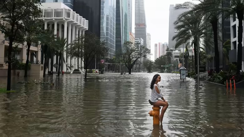 A person sitting in a flooded street Description automatically generated with medium confidence