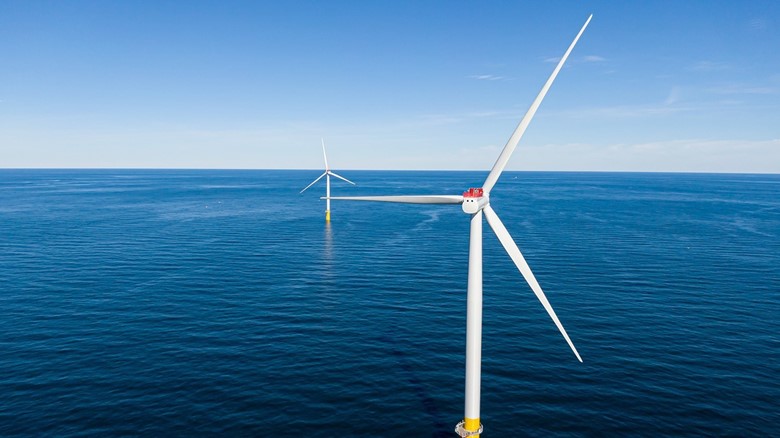 A couple of wind turbines in the ocean Description automatically generated with low confidence