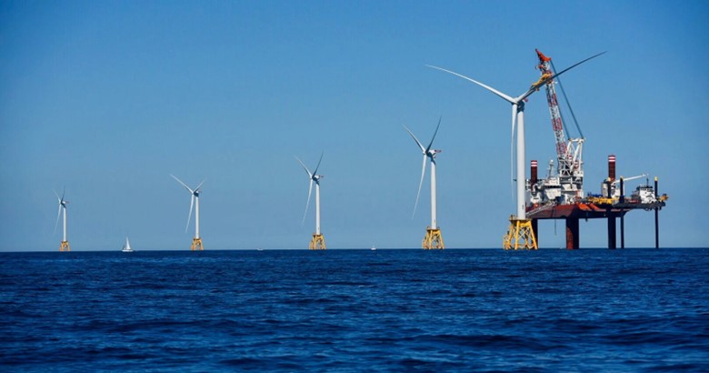 A group of wind turbines in the ocean Description automatically generated